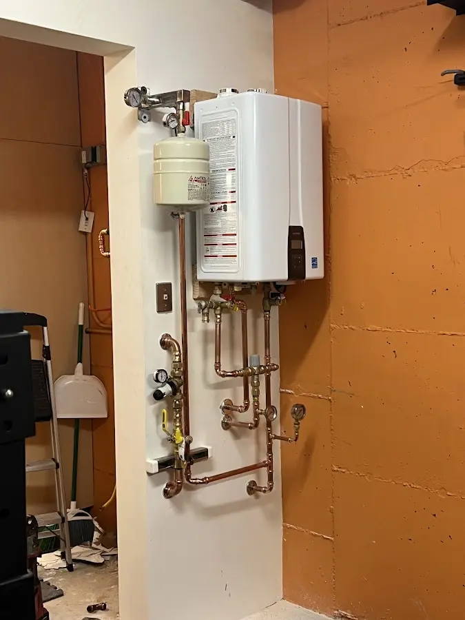 Plumbing technician inspecting water heater connections in Windsor